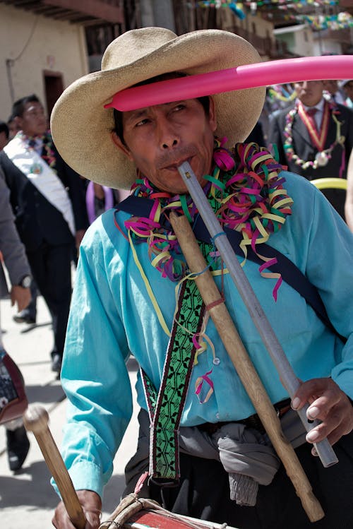 Man in Blue Dress Shirt Wearing Straw Hat Playing Flute