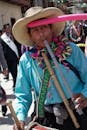 Man in Blue Dress Shirt Wearing Straw Hat Playing Flute