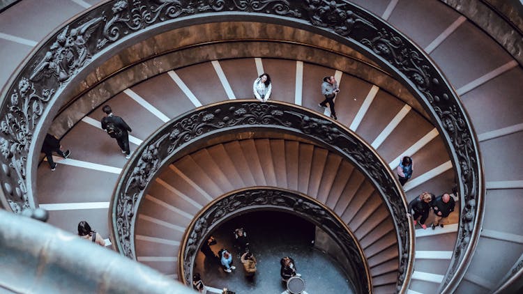 People Walking Down Spiral Stairs In Italian Museum 