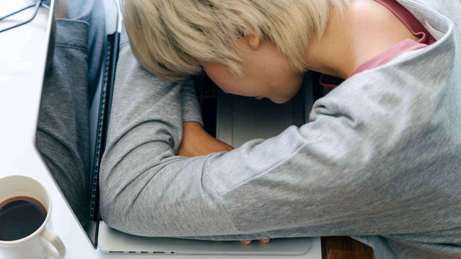 Modafinil for Multiple Sclerosis Fatigue: An Effective Solution From above of anonymous female in casual clothes resting head on netbook keyboard near cup of coffee after long working day — modafinil for multiple sclerosis fatigue