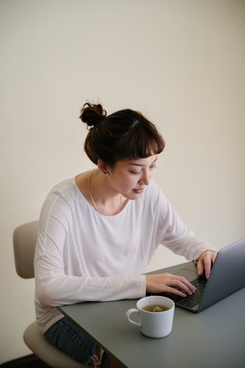 Pensive woman typing on laptop keyboard at home