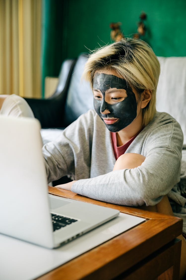 Young Woman With Facial Mask Using Laptop