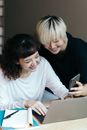 两名同事在室内兴奋地使用笔记本电脑和智能手机合作开展一个项目