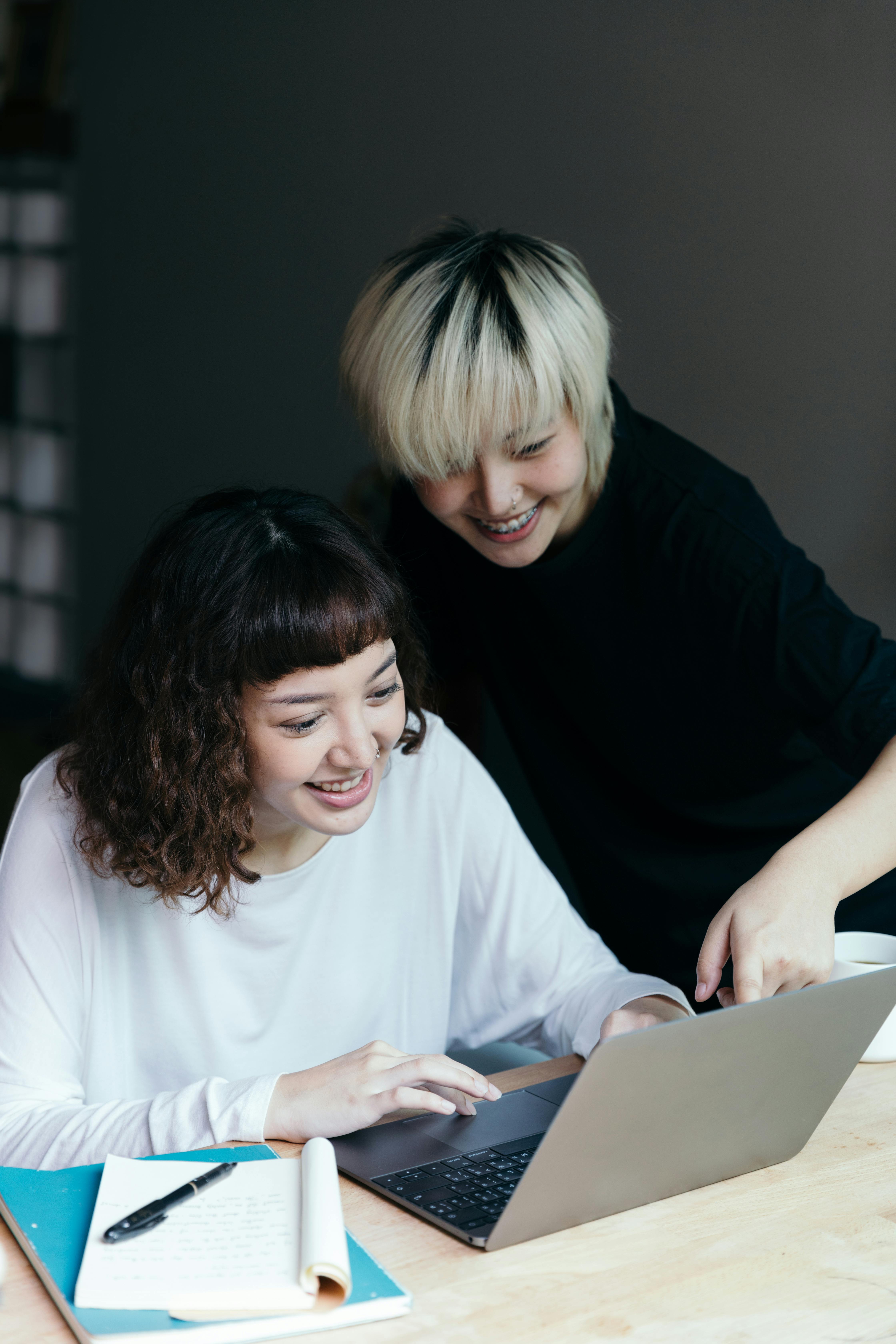 young girlfriends using laptop together in room