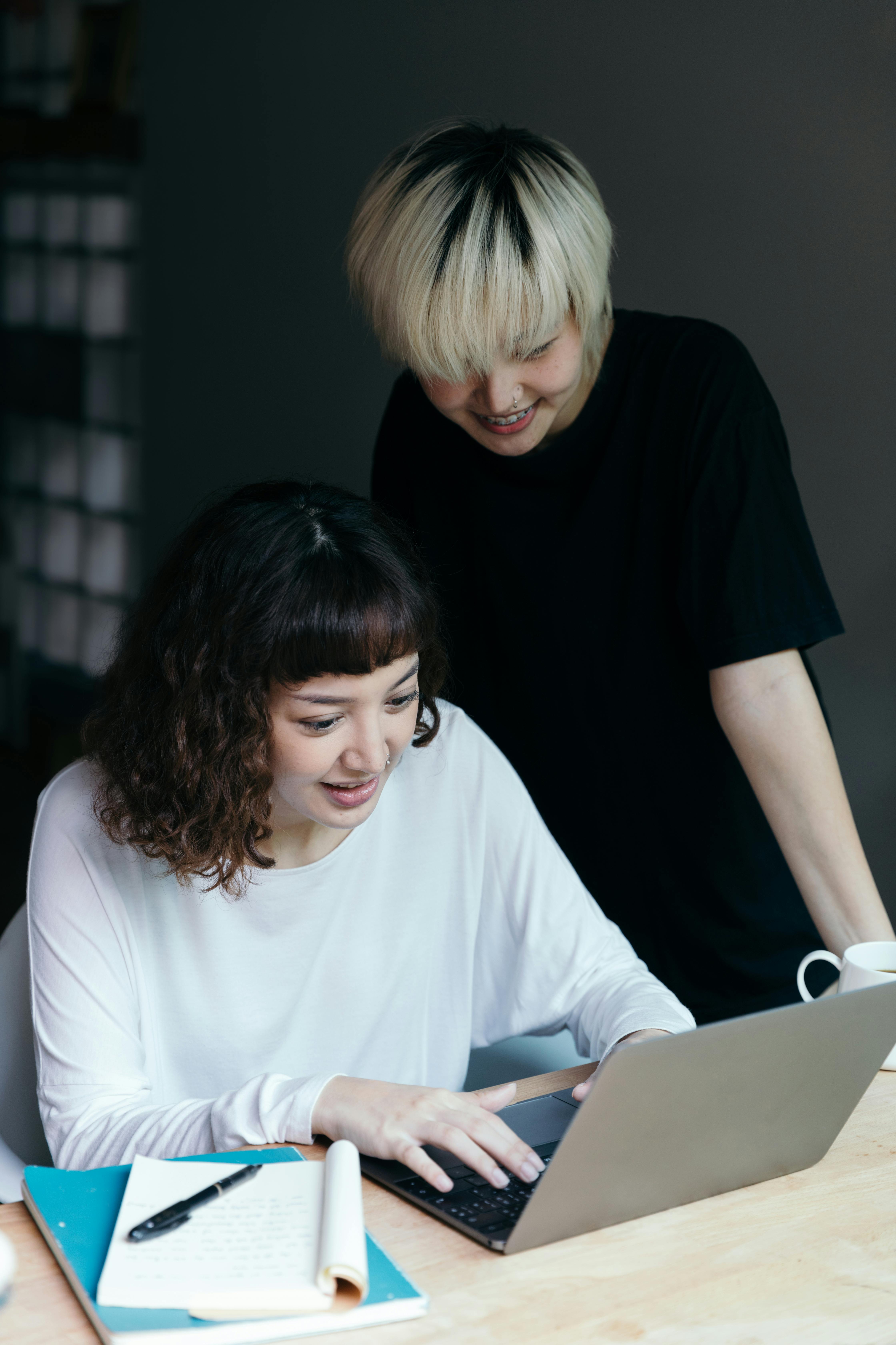 female students cheerfully using laptop together