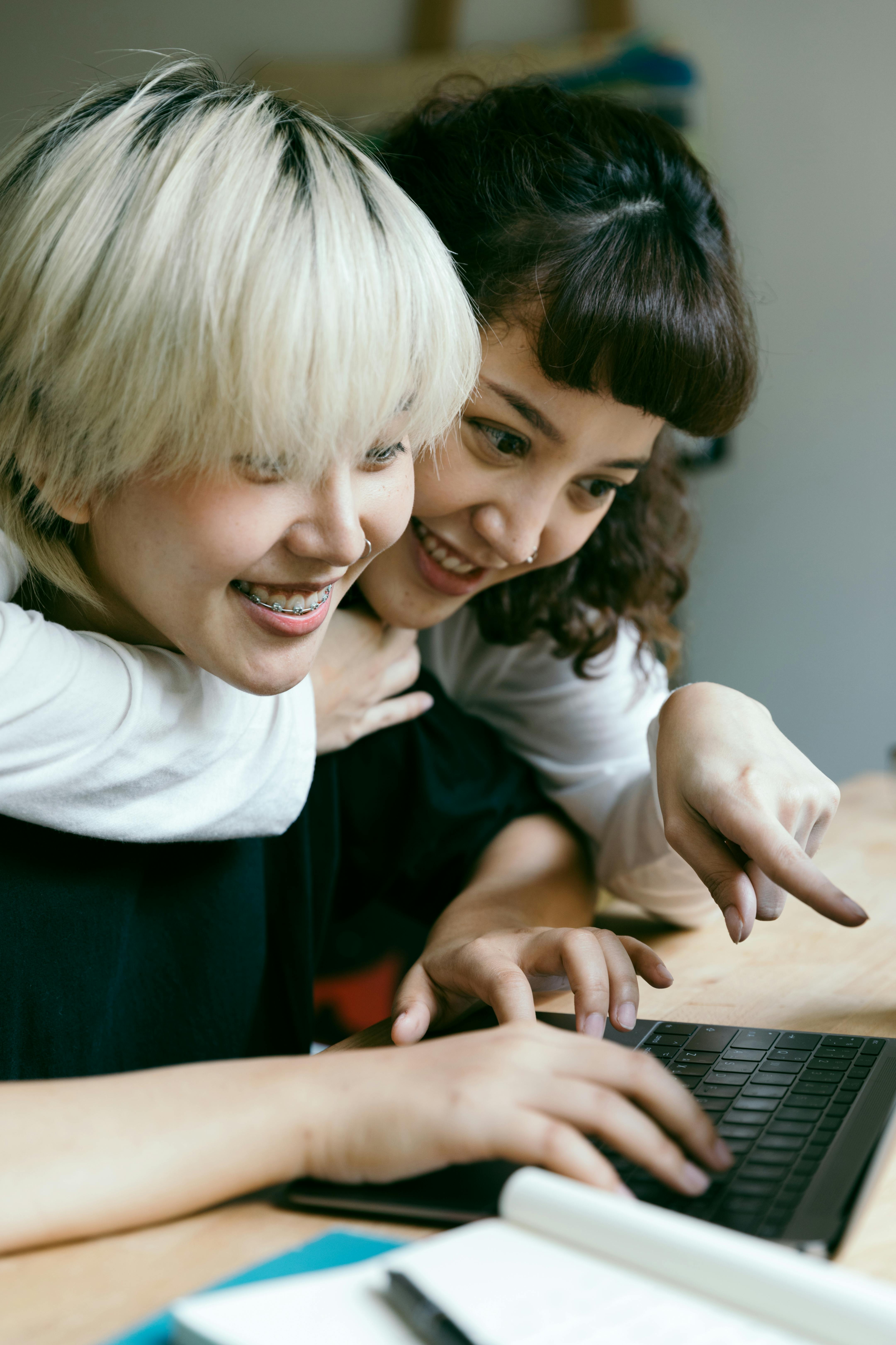 cheerful young girlfriends working on laptop