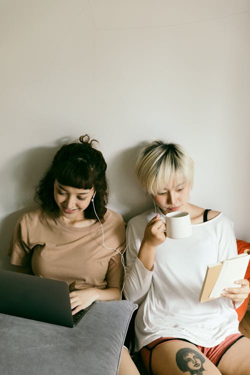 Free Women using laptop and reading book together Stock Photo