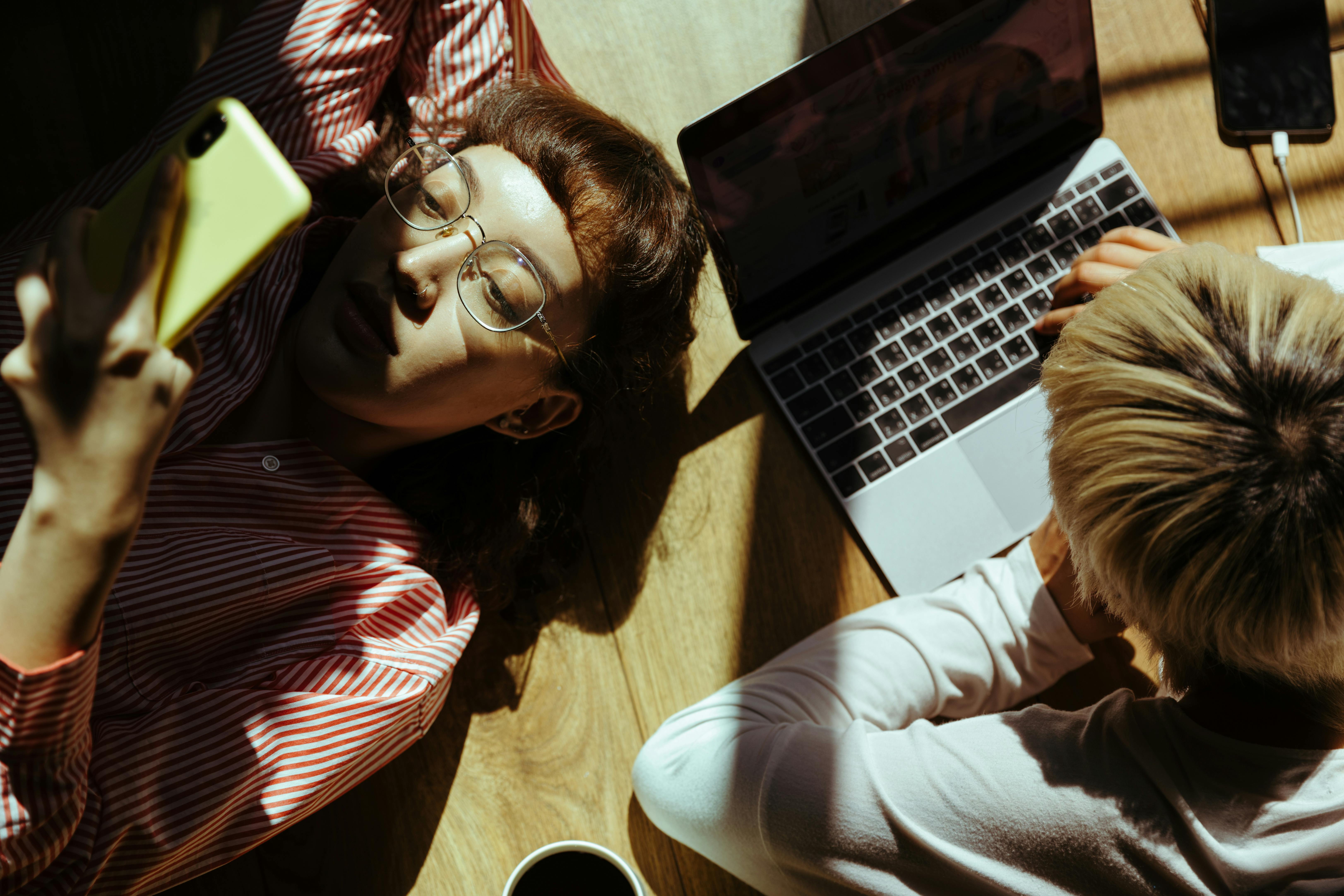 crop anonymous freelancer using laptop near girlfriend chatting on smartphone