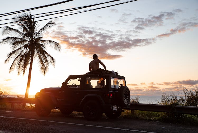 Silhouette Of Man Sitting On Roof Of A Jeep Wrangler