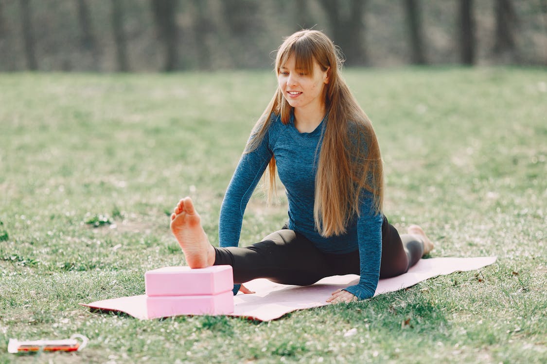 Free Positive young woman doing yoga with blocks on lawn Stock Photo