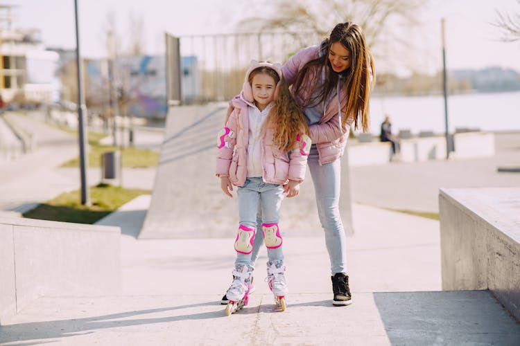 Happy Little Girl Practicing Skating On Roller Skates With Mother