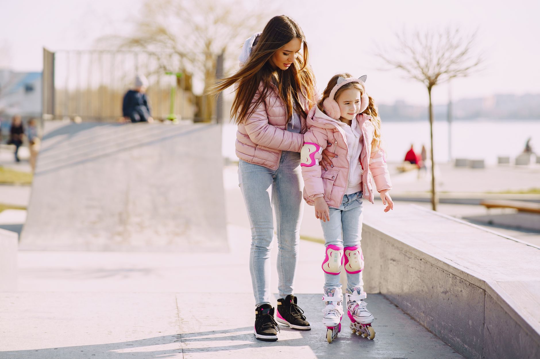 Parent helping child roller skate with pads