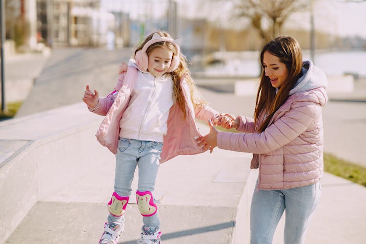 Smiling Little Girl Practicing Skating On Roller Skates With Mother