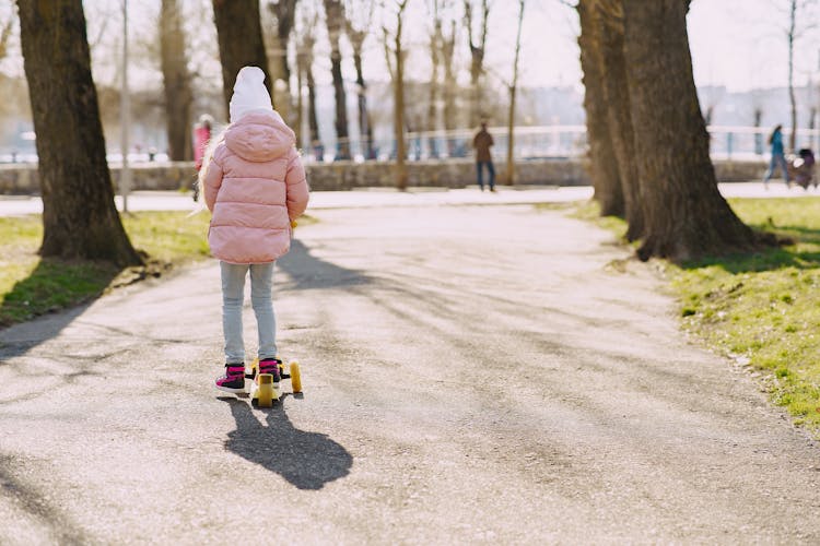 Child Ridding Kick Scooter On Path In Park