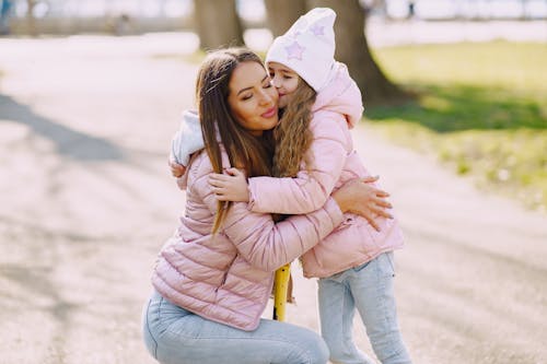 Girl kissing and hugging mom in park