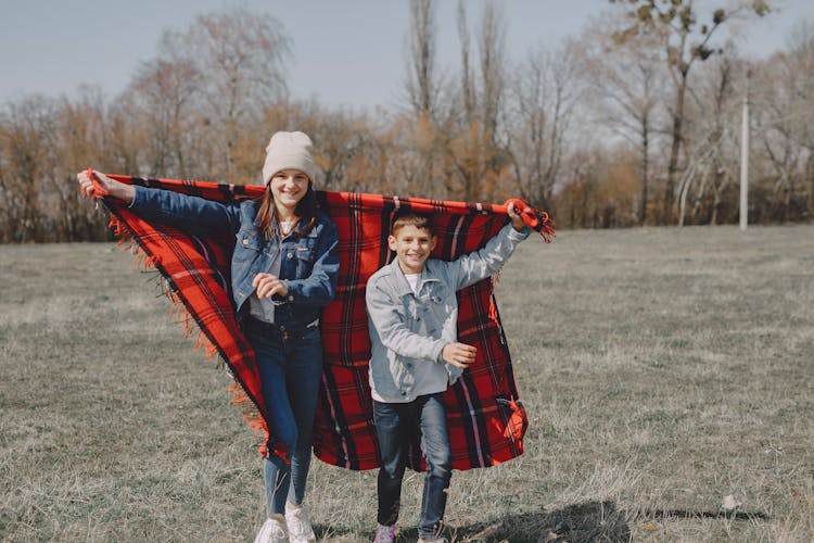 Cheerful Kids Running With Blanket In Lawn In Autumn Season