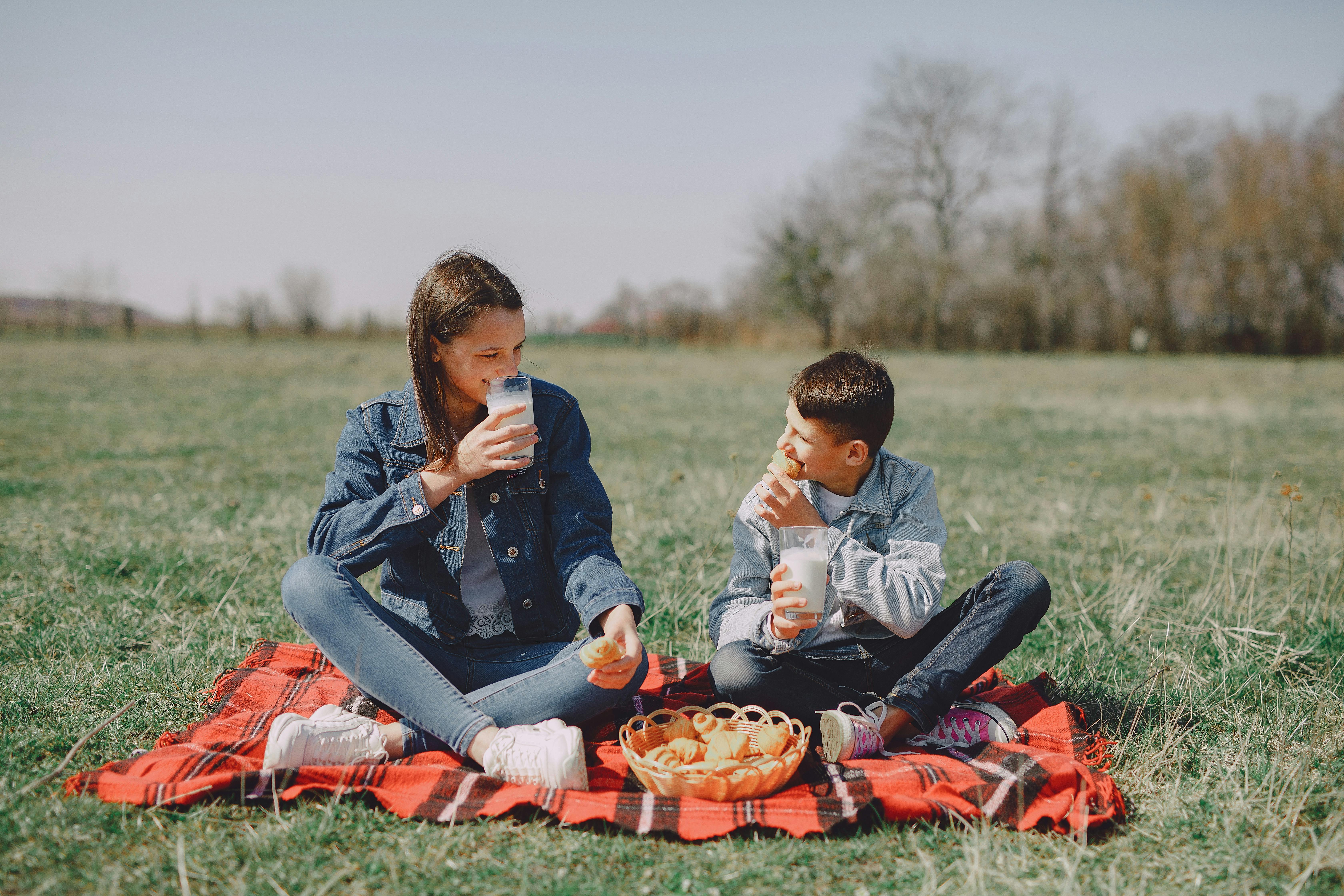 happy friends resting on plaid in park