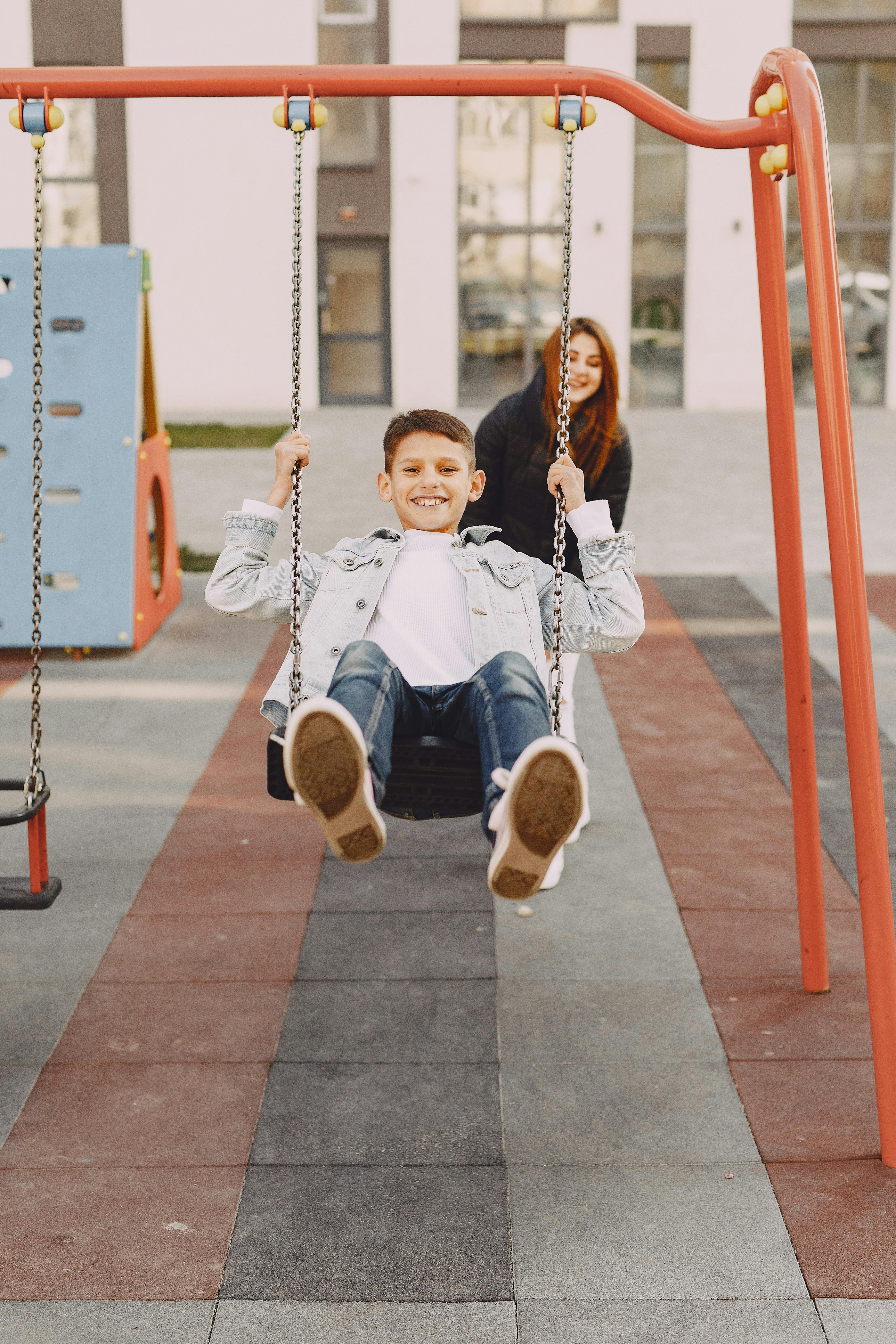 joyful boy swinging on swing on playground