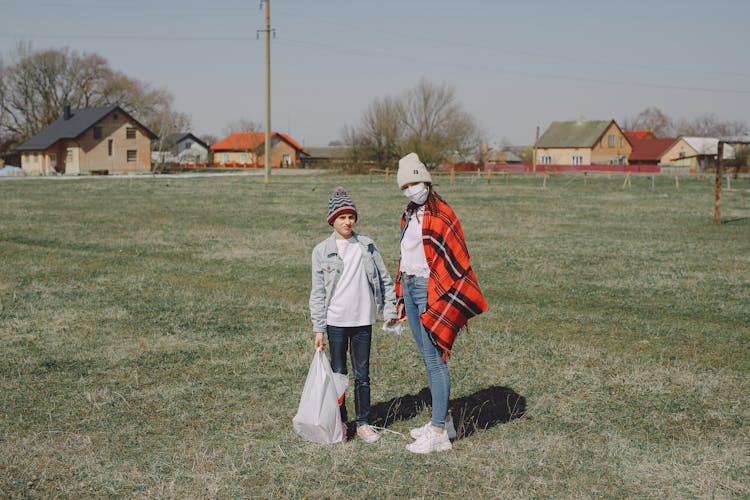 Young Boy And Girl Standing On Lawn Near Village