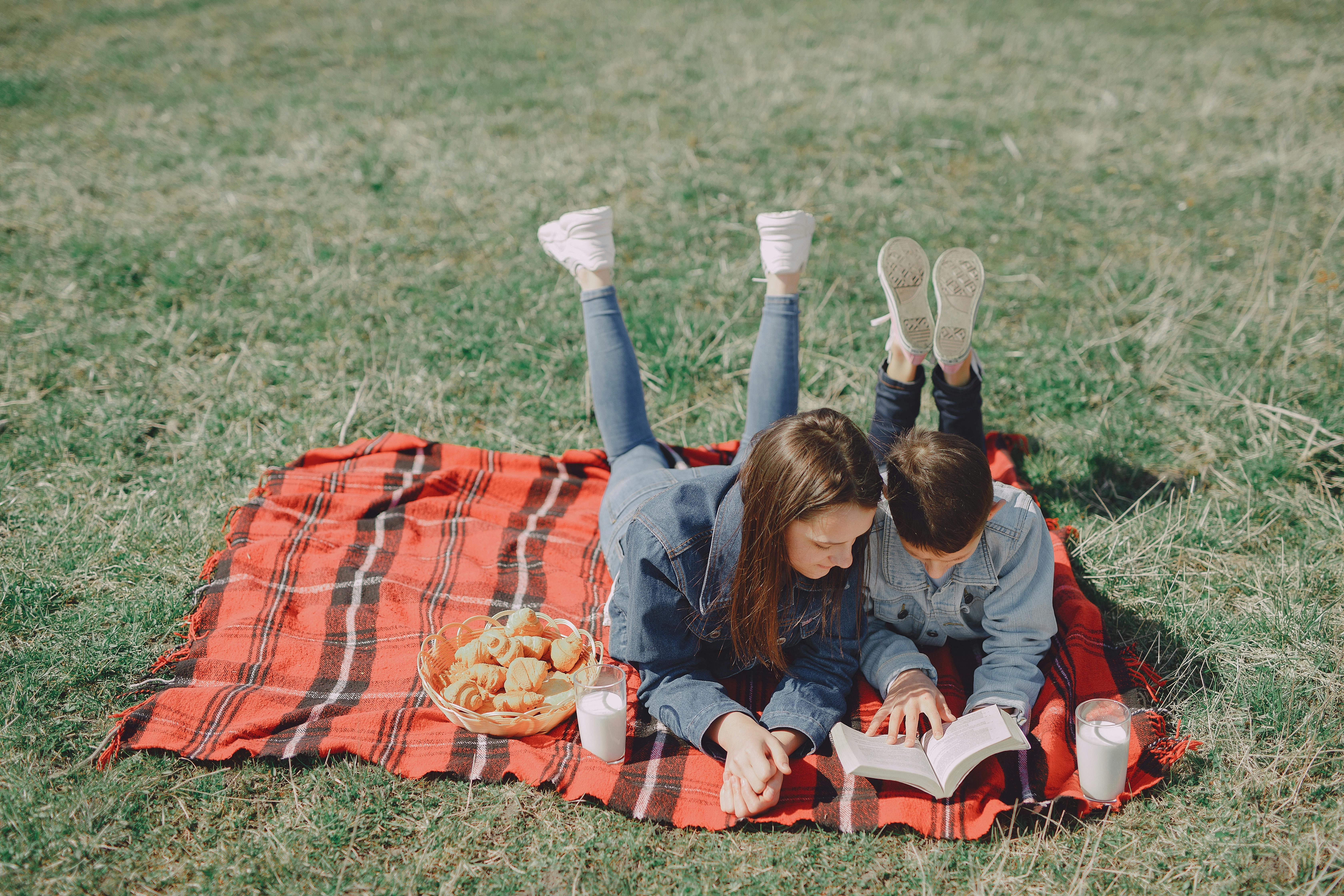 casual siblings resting on picnic in park