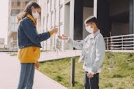 Young friends in mask disinfecting hands on city street