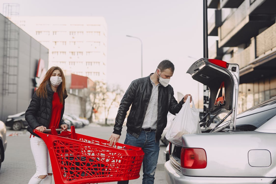 Couple in protective masks moving shopping bags to trunk