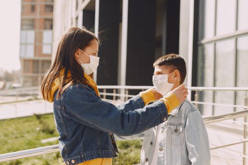 Free Side view of children in casual outfit and protective masks standing in front of each other while girl fixing protective mask on boy face Stock Photo