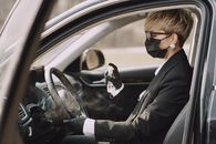 Woman in formal clothes disinfecting steering wheel of car