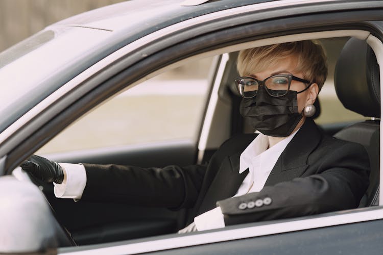 Serious Female Driver In Protective Mask And Gloves In Car