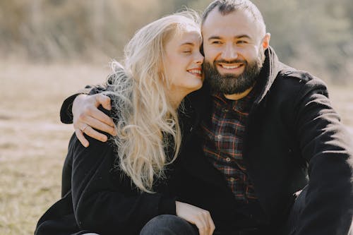 Happy couple hugging and smiling during rest in countryside meadow