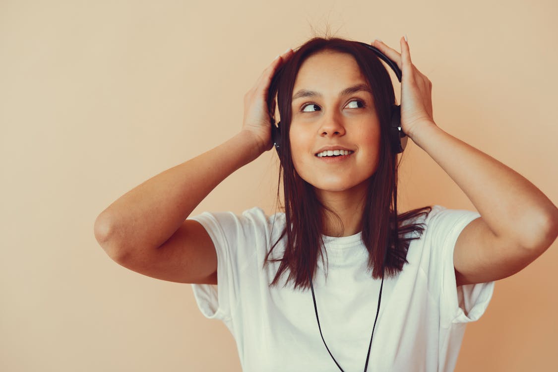 Free Dreamy young woman listening to music in headphones Stock Photo