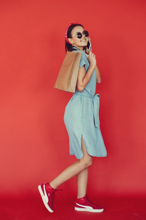 Positive woman with shopping bag talking on smartphone