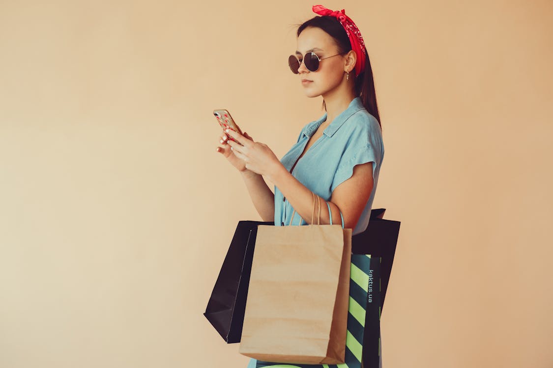 Calm woman with shopping bags using smartphone