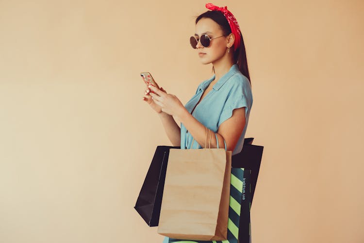 Calm Woman With Shopping Bags Using Smartphone