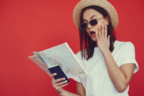 Free Young woman with passport and map on red background Stock Photo