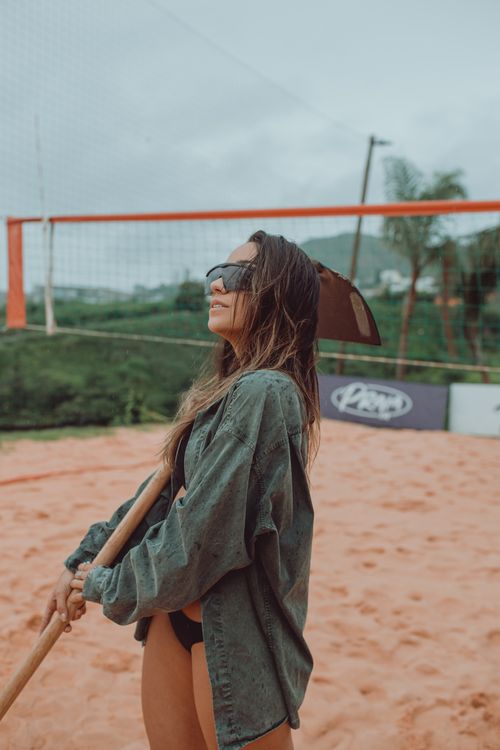 Free Fashionable woman in sunglasses and casual outfit on a sandy volleyball court. Stock Photo