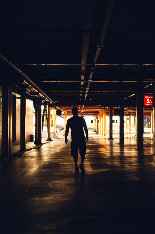Free Full body silhouette of male walking along rows of columns on parking area Stock Photo