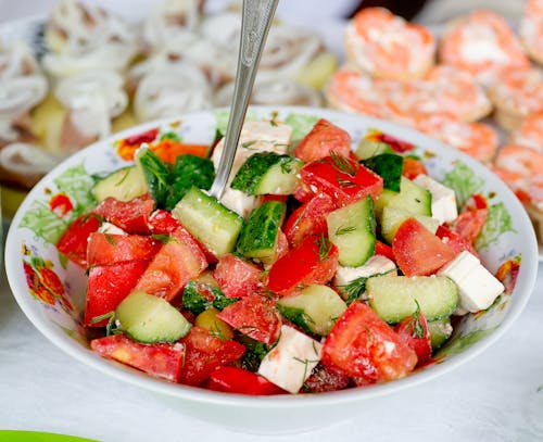 Salad of fresh cucumber and tomatoes mixed with cheese and parsley on table in bright room