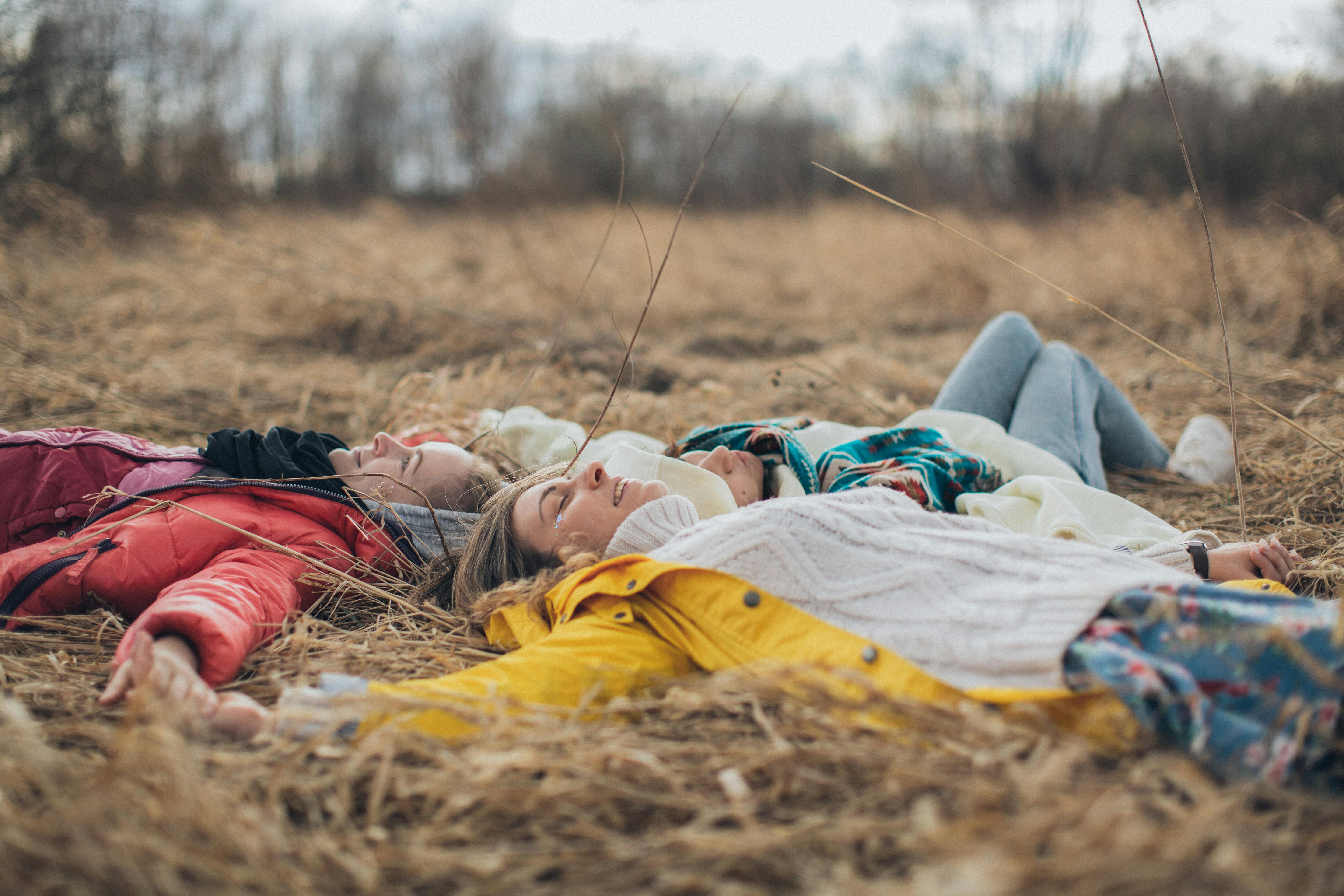 relaxed friends lying on grass in circle