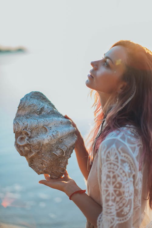 Delighted woman with big shell on seashore