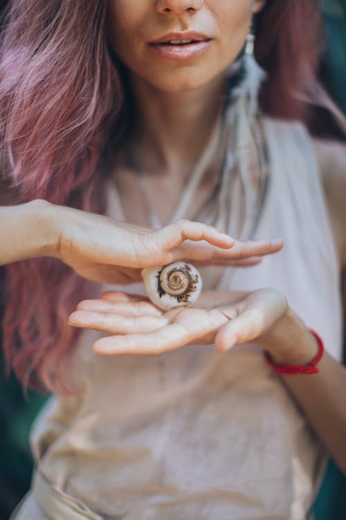 Crop woman with seashell in hands