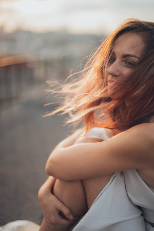 Free Young woman sitting on rooftop in windy weather Stock Photo