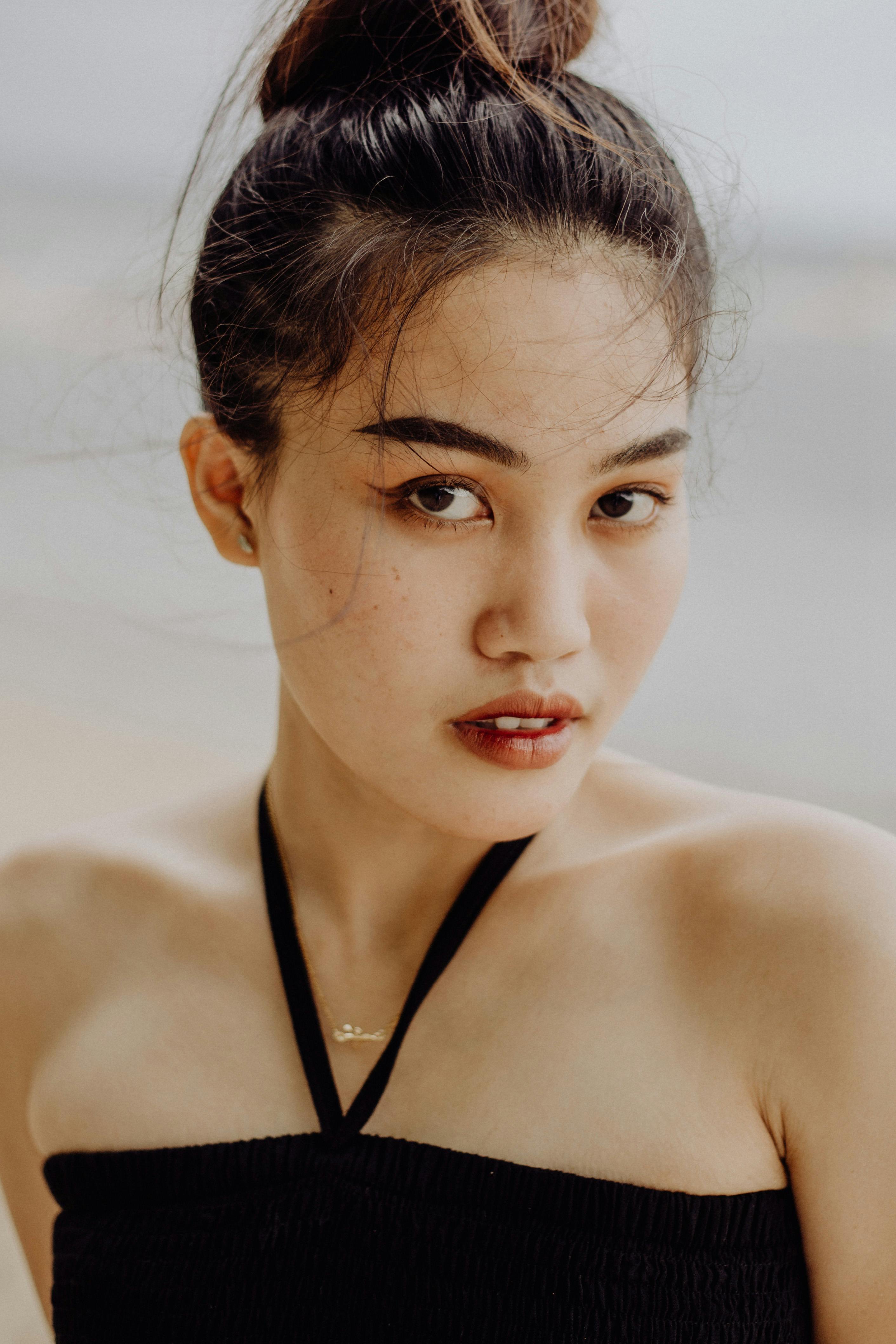 Elegant portrait of a young woman with a hair bun and halter dress, shot in natural light.