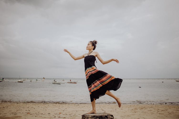 Woman In Black And Black Dress Posing On The Shore Of A Beach