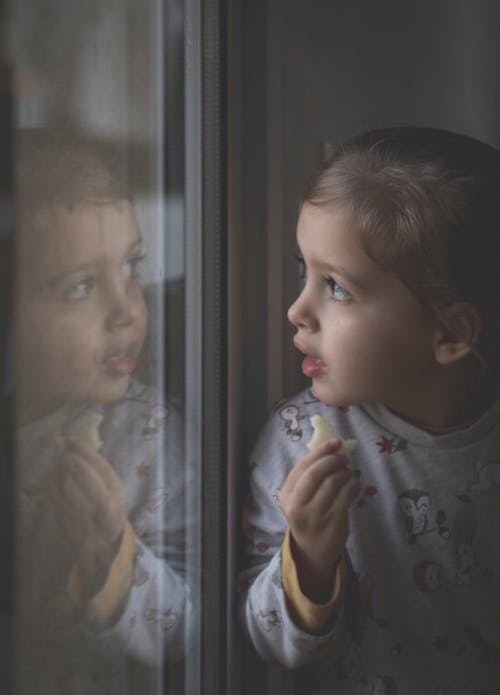 Cute Little Girl Looking through the Glass Window