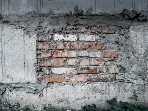 Aged grunge wall with bricks and gray concrete blocks in plaster and cement