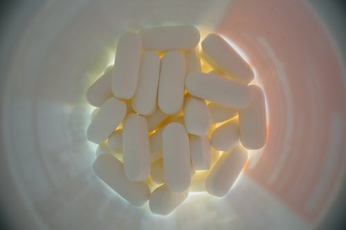 Top view of plastic jar filled with white medical pill in soft light