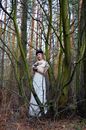 Mysterious woman standing in spooky woods
