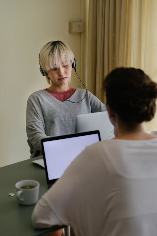 Girlfriends using laptops and headphones in living room
