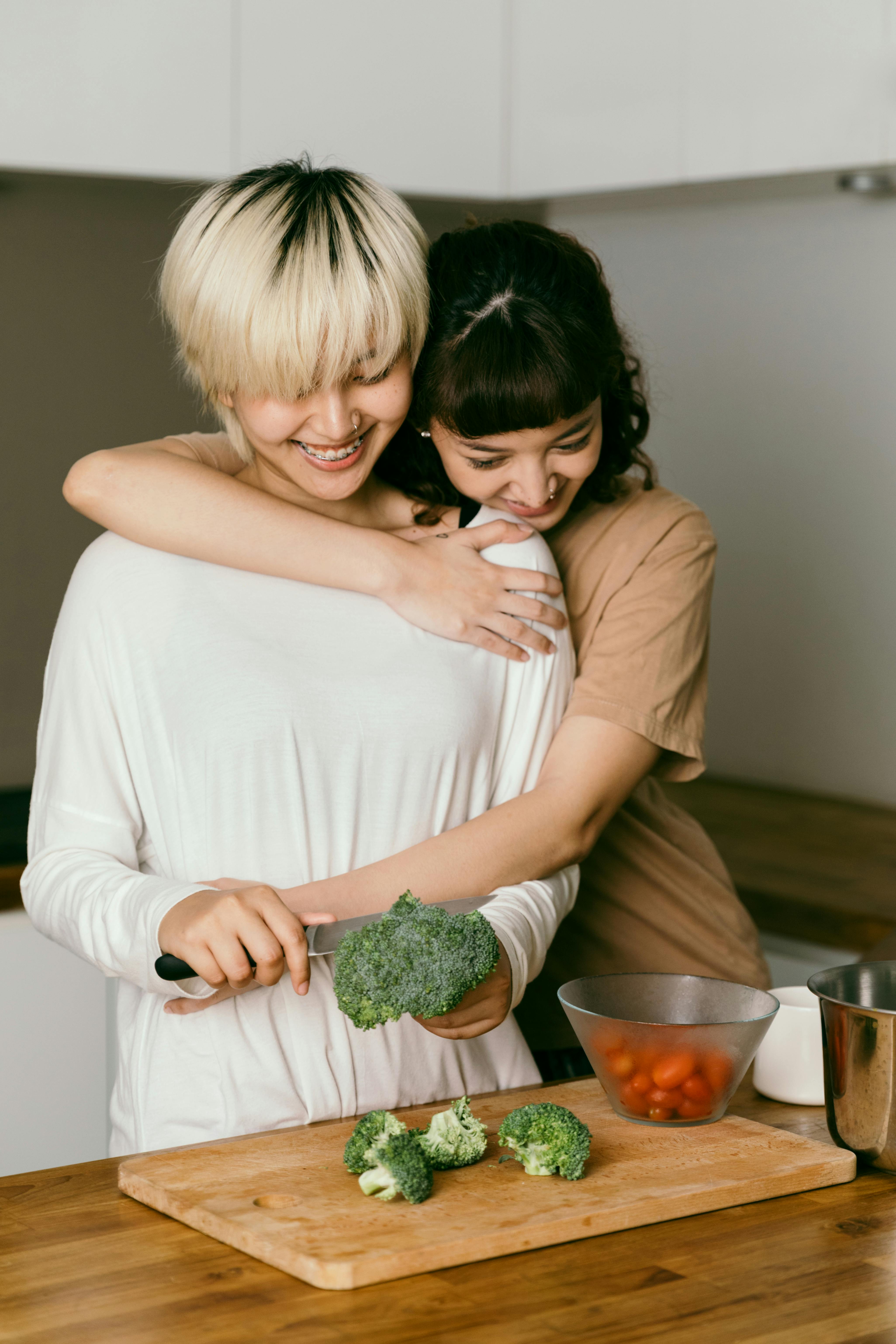 woman being hugged while making dinner